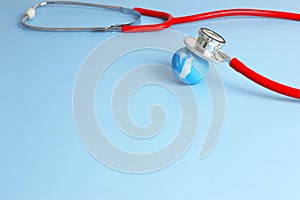 Checking health with red stethoscope on earth. World health day concept - blue earth with on light blue background