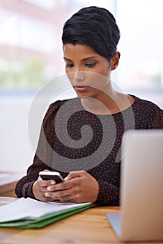 Checking her calendar. A beautiful young woman sending a text message while sitting in her office.