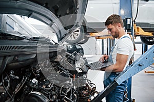 Checking if product is avaible now. Employee in the blue colored uniform works in the automobile salon photo