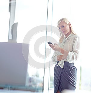 Checking through my daily emails. a pretty business woman looking at her cellphone with copyspace.