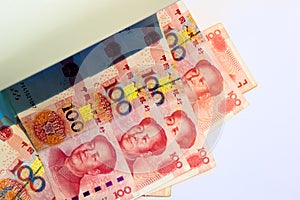 Checking one hundred chinese yuan banknotes with ultraviolet light or black light machine on white background.