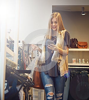 Checking shopping off my to-do list for the day. a young woman using her cellphone while out shopping.