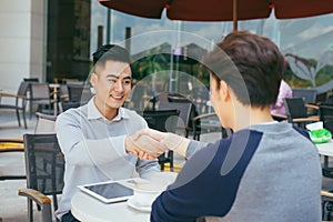 Checking stocks. Two business partners working on the laptop smiling cheerfully on a meeting at the local cafe - Image