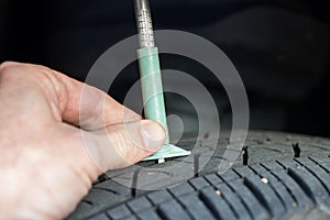 Checking tread depth on a tire with a tire gauge