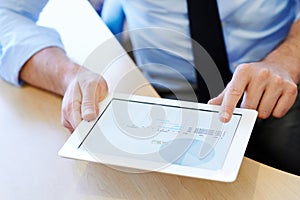 Checking up on the financial data. Cropped closeup shot of a businessman working on a digital tablet.