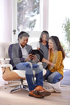 Checking up on what daddys doing. Full length shot of a young family looking at a digital tablet together.