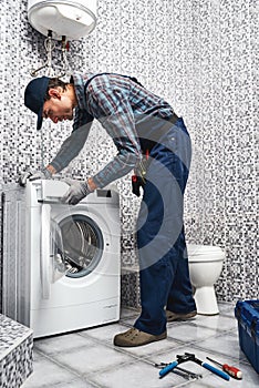 Checking washing machine work. Working man plumber in bathroom