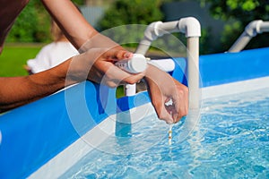 Checking the water quality of a pool with the help of a test strip with PH value, chlorine and algaecide