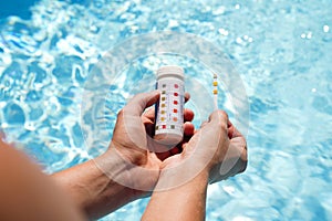 Checking the water quality of a pool with the help of a test strip with PH value, chlorine and algaecide