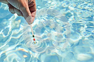 Checking the water quality of a pool with the help of a test strip with PH value, chlorine and algaecide
