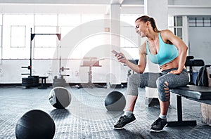 Checking where her gym buddies are. a woman using a cellphone in a gym.