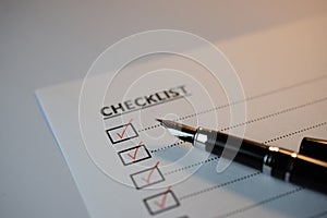 Checklist concept - checklist box with red checkmark, paper and a pen with checklist word on table