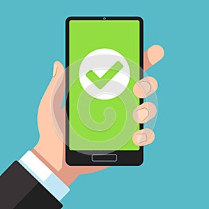 Checkmark on smartphone screen. Hand holding smartphone with green tick. Phone surveys technology, website app testing photo