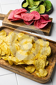 Cheddar  Sour Cream Flavored Potato Chips on white ceramic squared tile table background photo