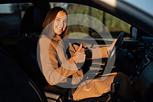 Cheeeful young woman is driving a car