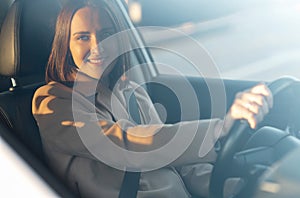 Cheeeful young woman is driving a car