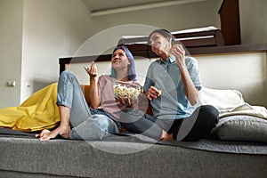 Cheeful lesbian couple watching comedy sitting on couch