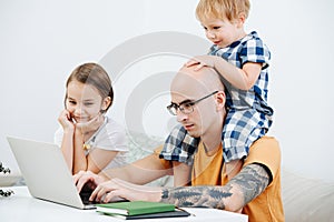Cheeky bored kids messing with their father working on his laptop