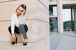 A cheeky business lady squatting. extravagant squatgirl in a business-style suit