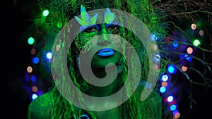 Cheeky Mystic green dryad in UV fluor black light with Glowing trees on background. Fantasy concept.