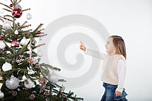 Cheeky toddler girl pointing towards the tip of the Christmas tree