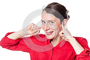 Cheeky young woman smiling in plugging fingers in ears