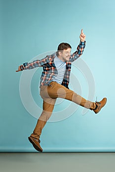 Cheer, joy. Young happy bearded man in casual clothes jumping isolated on light blue background.