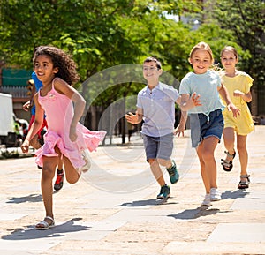 Cheerful active children are racing along the street