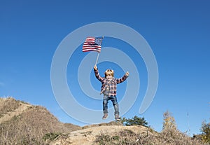cheerful active little boy joyfully twitching and waving american flag against cloudless blue sky