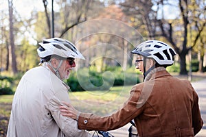 Cheerful active senior couple with bicycle in public park together having fun. Perfect activities for elderly people. Happy mature