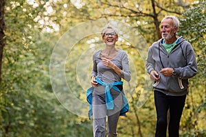 Cheerful active senior couple jogging in the park