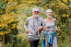 Cheerful active senior couple jogging in the park