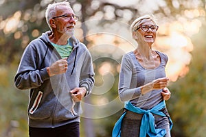 Cheerful active senior couple jogging in the park