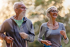 Cheerful active senior couple jogging in the park