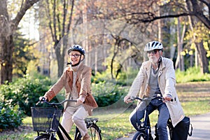 Cheerful active senior couple riding bicycles in public park together having fun. Perfect activities for elderly people.
