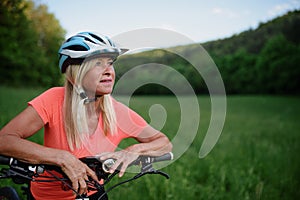 Cheerful active senior woman biker outdoors in nature.