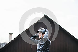 A cheerful active senior woman standing outdoors, putting on bicycle helmet.