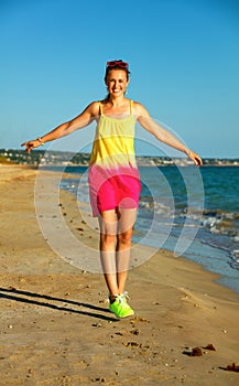 Cheerful active woman on seashore in evening having fun time