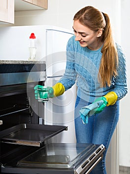 Cheerful adult girl in gloves removing snuff in oven