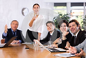 Cheerful adult man watching presentation at work meeting in office