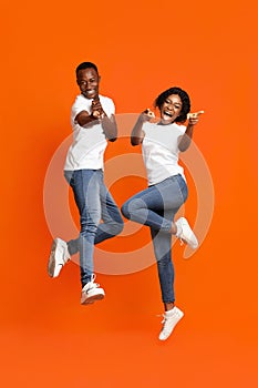 Cheerful african american couple indicating at camera and jumping up