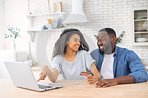 Cheerful African-American couple shopping online at home