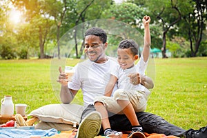 Cheerful african american father and son having a picnic in the park, Happiness family concepts