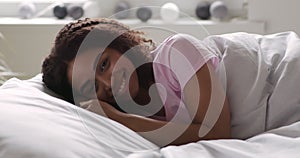 Cheerful african american girl lying in bed