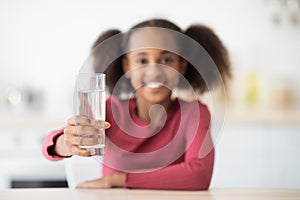 Cheerful african american girl teenager holding glass of water