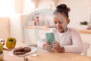 Cheerful African-American girl watching cartoon on the smartphone