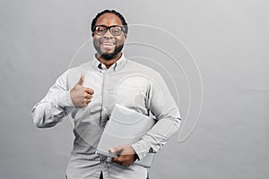 Smart African-American man using a laptop, isolated on grey