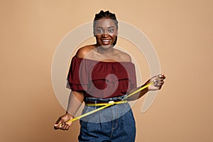 Cheerful african american slender woman measuring her waist