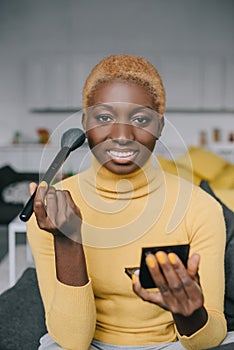 Cheerful african american woman applying powder photo