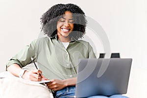 A cheerful African-American woman interacts with her laptop